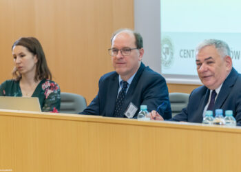profesor Paweł Kras siedzi przy stole podczas konferencji wraz z innymi uczestnikami
